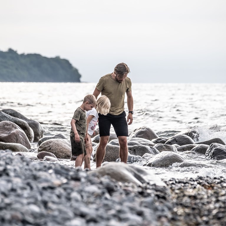 Far og børn leder efter fossiler på stranden
